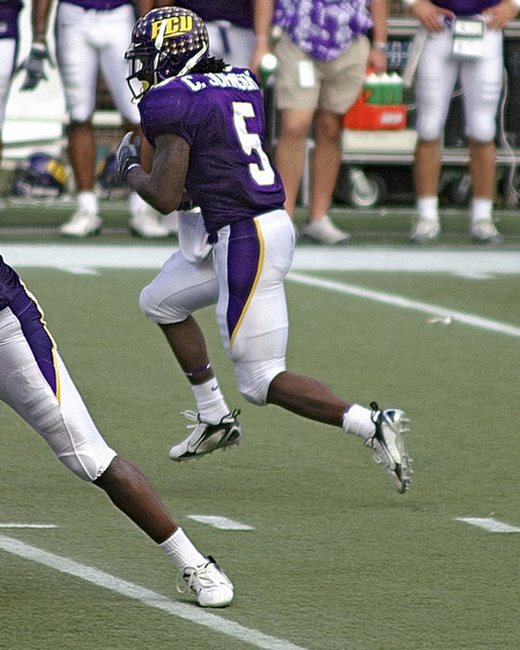A college running back carrying the ball upfield.